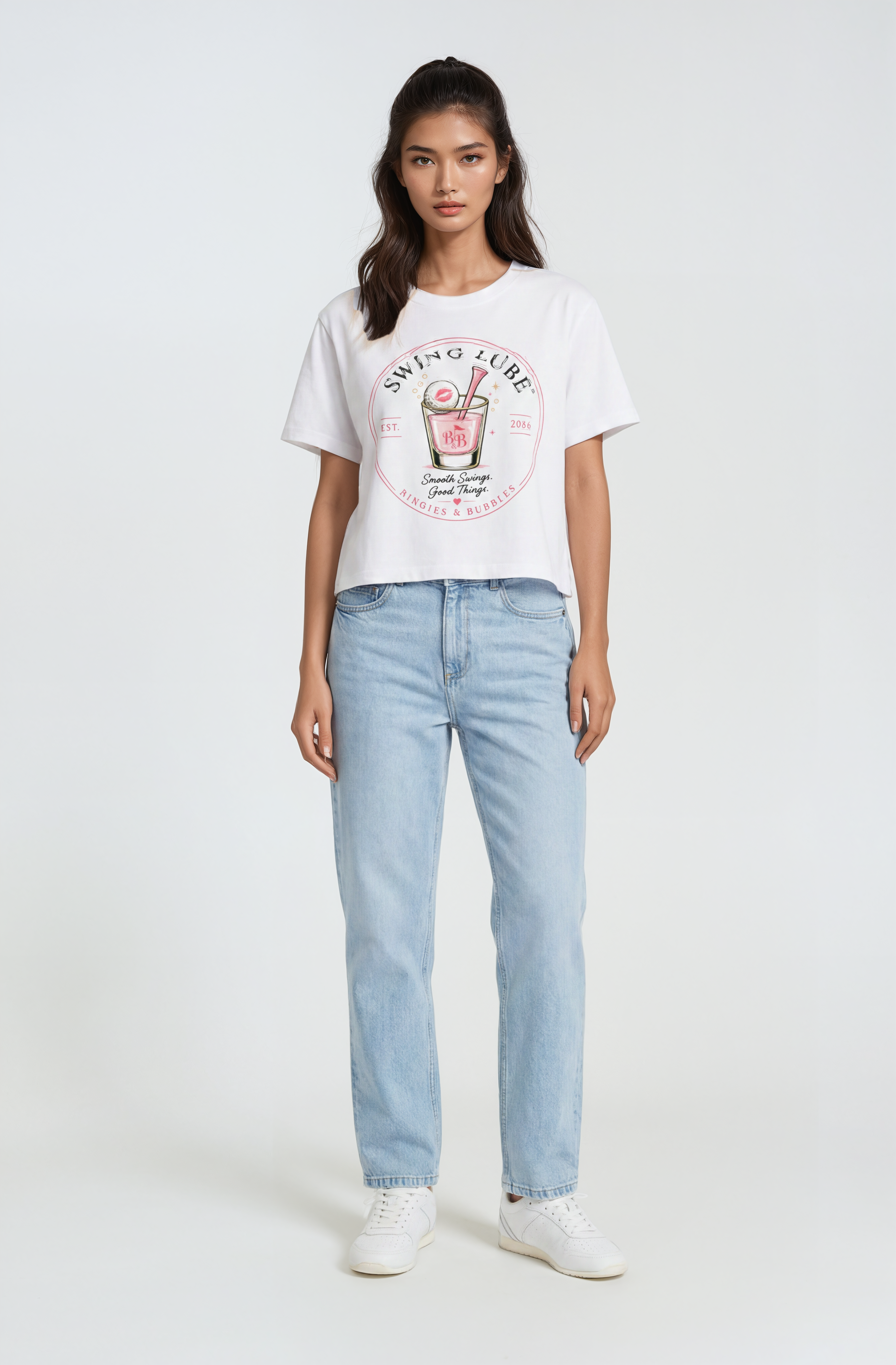 Woman wearing a white t-shirt with a graphic design and light blue jeans on a white background