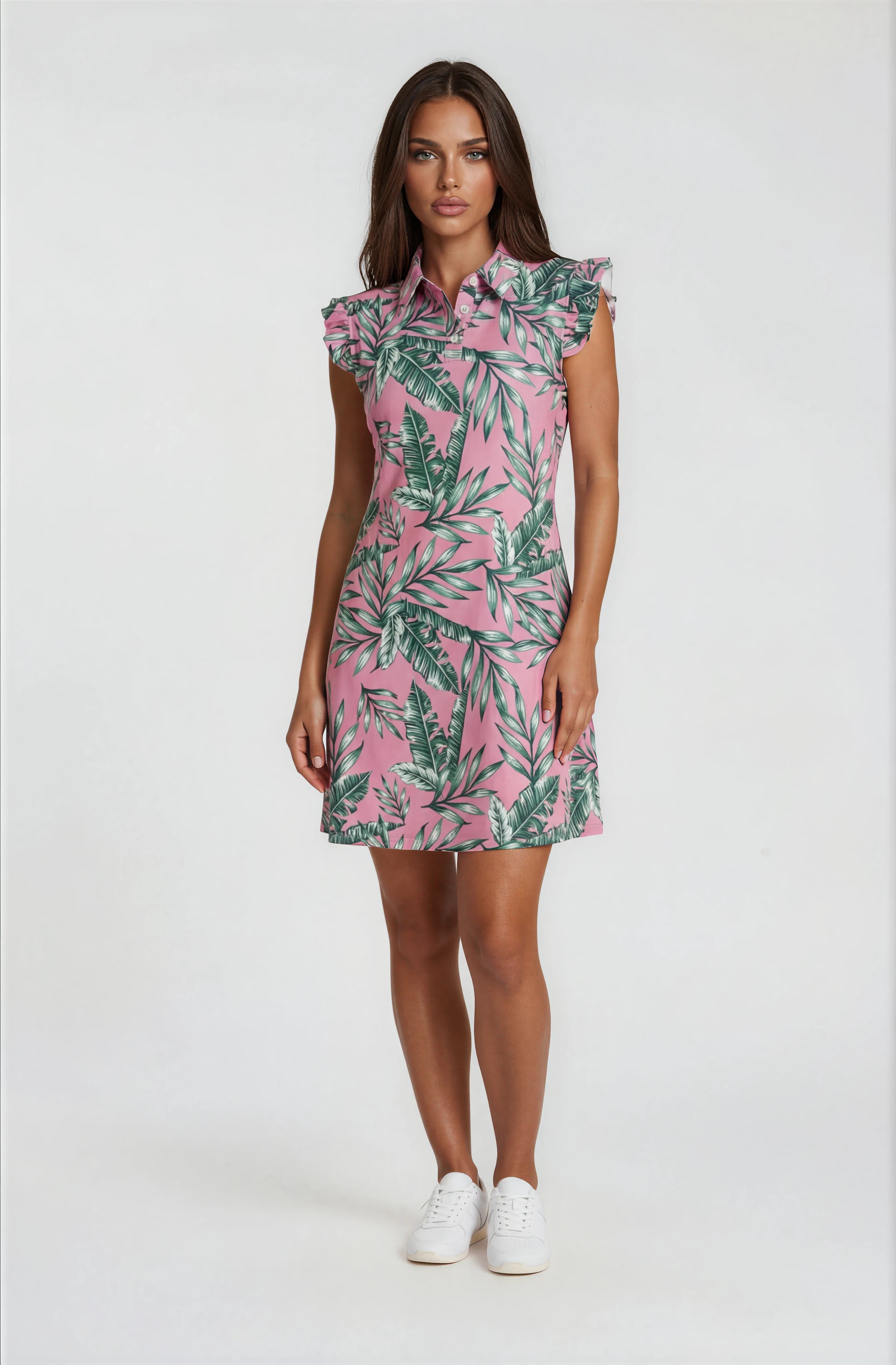 Woman wearing a Birdies and Bubbles pink dress with green leaf pattern on a white background