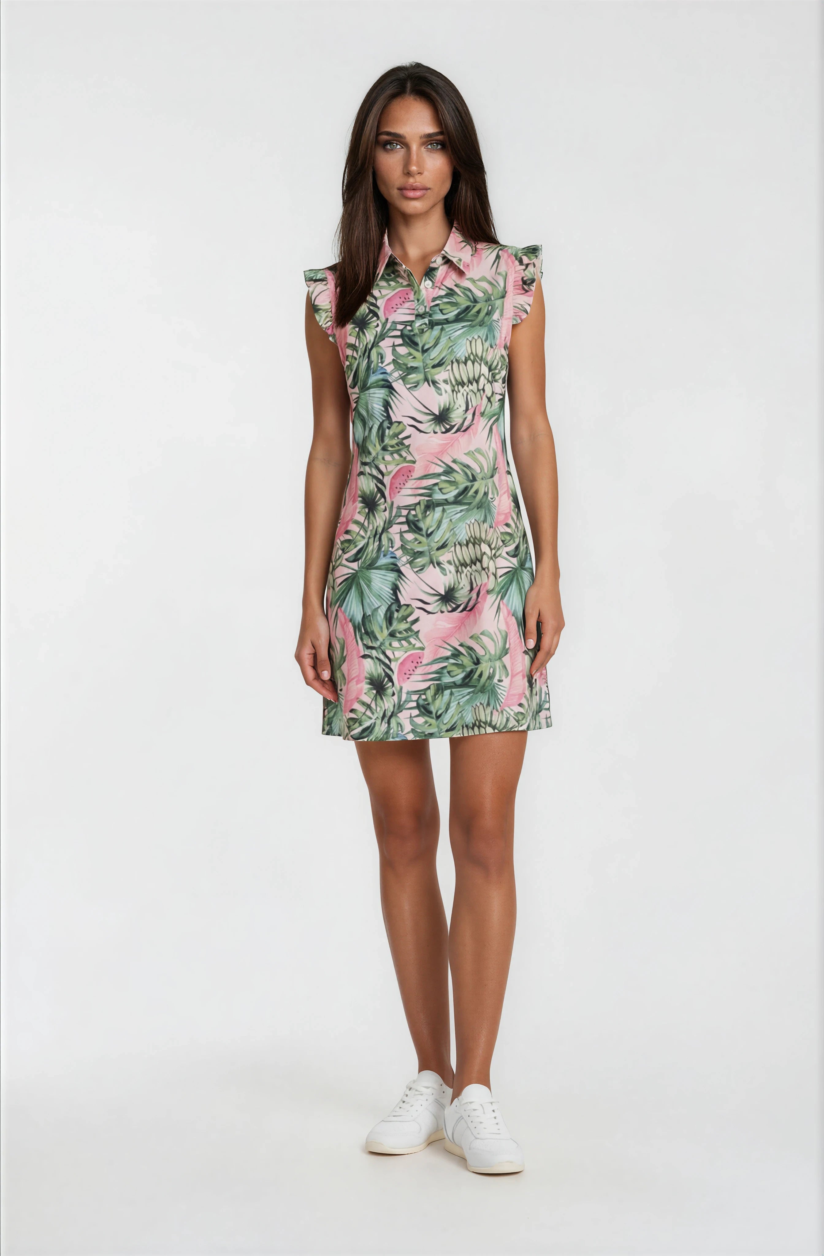 Female model wearing a pink watermelon print golf dress with green tropical leaves and ruffle sleeves