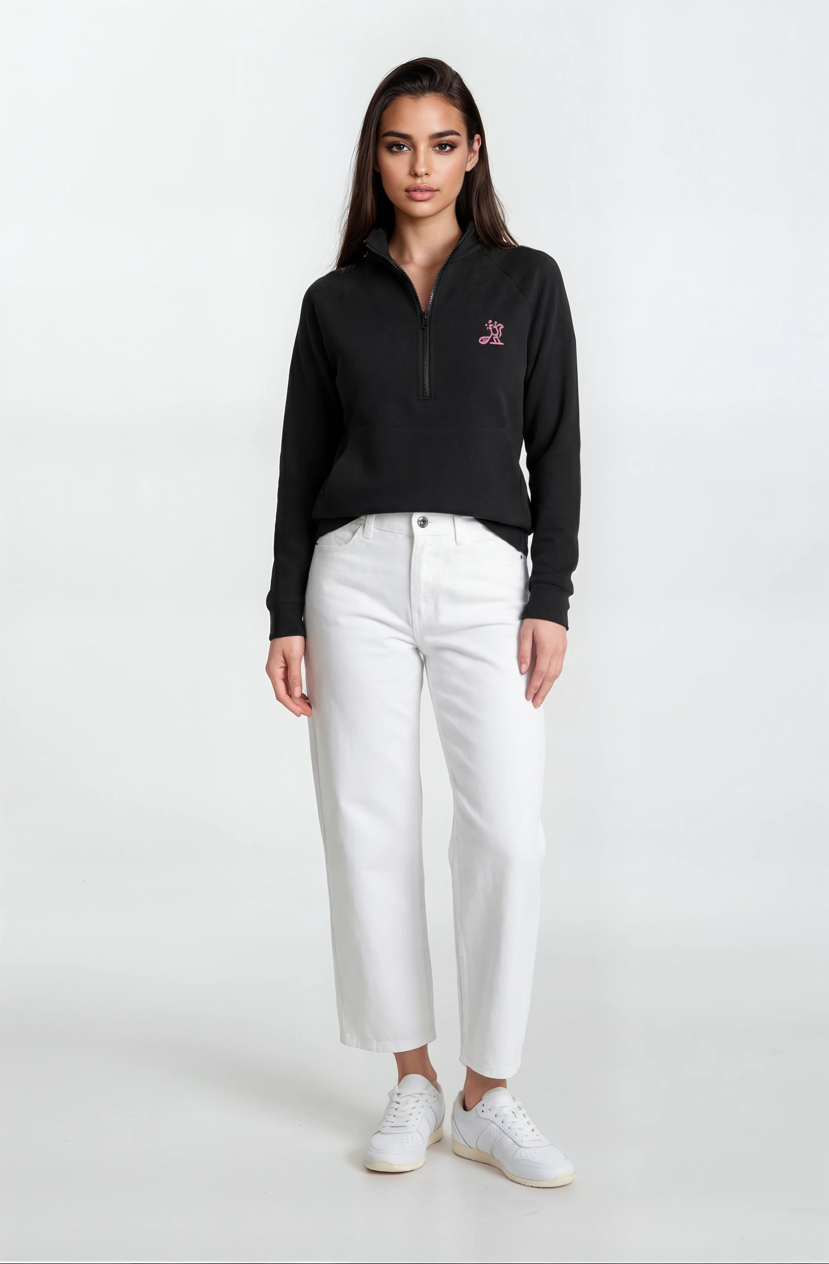 Woman wearing a black sweater with a logo and white pants on a white background
